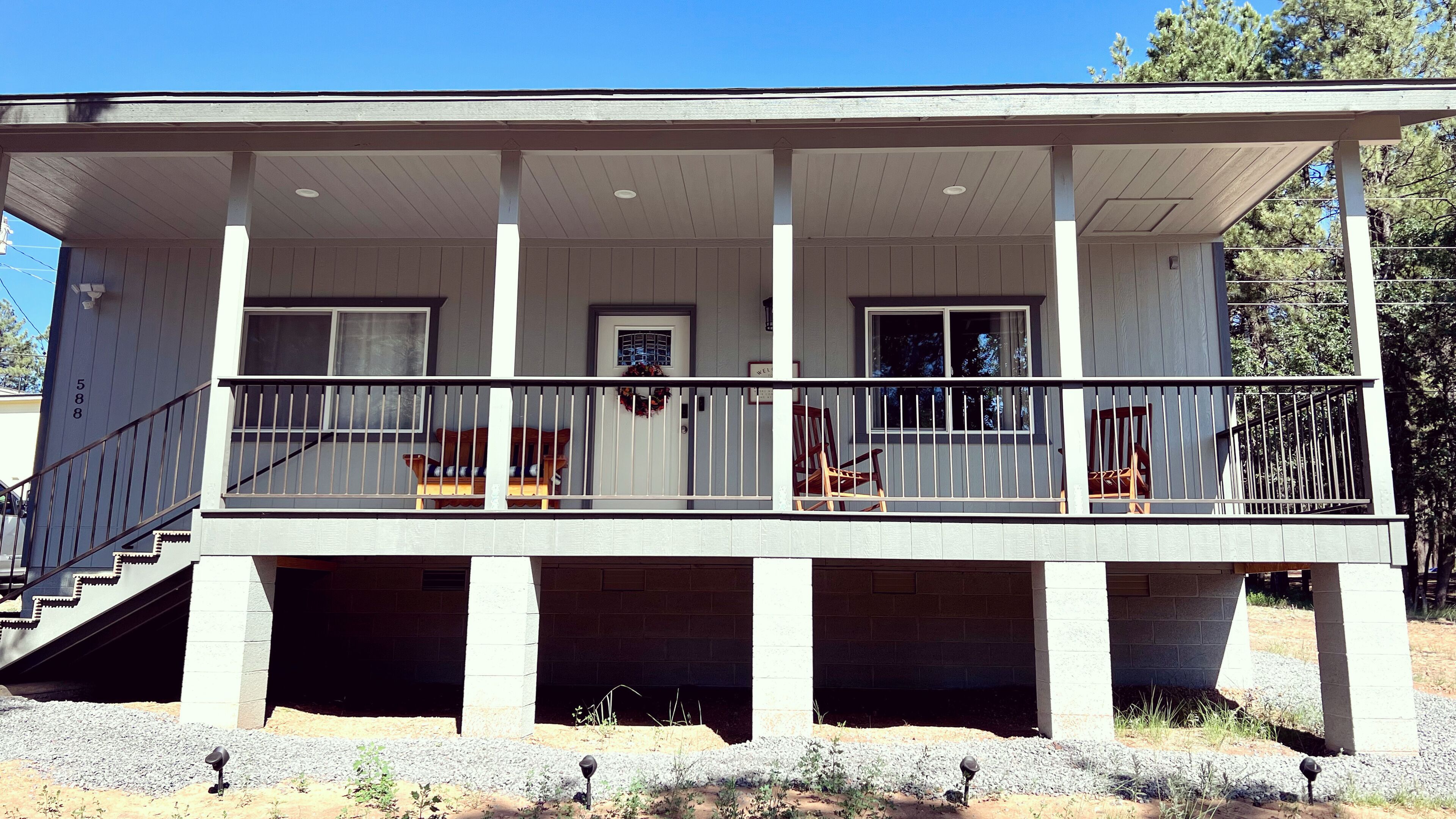 A two-story building with a covered balcony, a staircase leading to the upper floor, and a door with a wreath.