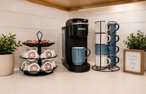 Eine KĂŒche mit einer Keurig-Kaffeemaschine, einer Kaffeetassen-Tablett und einem Kaffeetassenhalter.