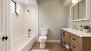 A bathroom with a bathtub, toilet, vanity, and a mirror. - Spacious 10BD Home - 12 min NYC & MetLife (Bayonne)