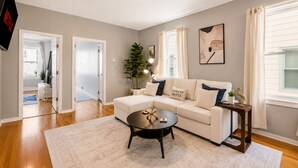 A living room with a sofa, coffee table, and a plant. - Spacious 10BD Home - 12 min NYC & MetLife (Bayonne)