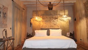 Quarto com uma cama grande, luminária pendente e tapeçaria na parede.