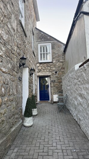 A stone building with a blue door, a small potted tree, and a metal table. - Minster Panorama is a beautifully restored three story Georgian Town House located on the famous "Th (St Ives)