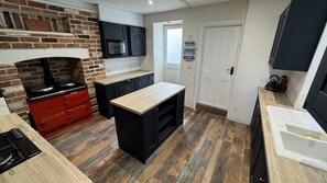 A kitchen with a brick wall, a microwave, a stove, and a sink. - Minster Panorama is a beautifully restored three story Georgian Town House located on the famous "Th (St Ives)