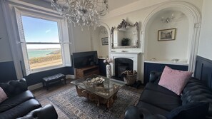 A living room with a TV, fireplace, and a view of the beach. - Minster Panorama is a beautifully restored three story Georgian Town House located on the famous "Th (St Ives)