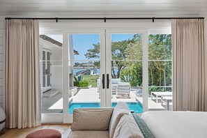 Ett sovrum med utsikt över en pool och en utomhusplats med sittmöbler.