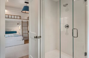 A room with a bunk bed, a glass-enclosed shower, and a door with a handle. - 711 Palm - DOCK - PLUNGE POOL - BIG  YARD - GRILL - FIREPIT (Isle of Palms)