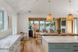 Une cuisine moderne avec des plans de travail en marbre, un revêtement de sol en bois et des luminaires suspendus.