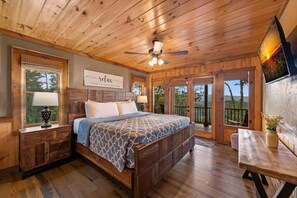 Ein Schlafzimmer aus Holz mit Bett, Nachttischen, Deckenventilator, Fernseher und Blick ins Freie.