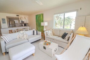A modern living room with a sofa, armchair, and a coffee table. There is a kitchen in the background with a dining area. - Ocean Village Club J36, 2/2 in Gated Community! (St. Augustine)