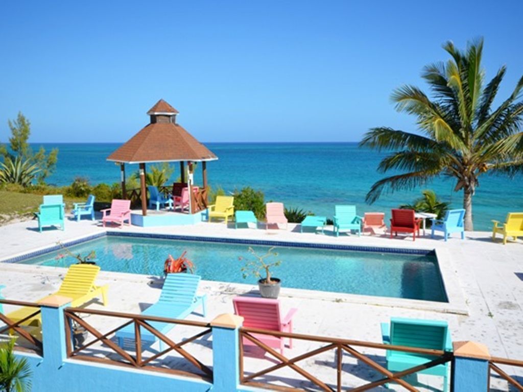 A pool area with colorful lounge chairs and a gazebo.