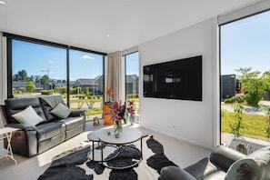 Ein modernes Wohnzimmer mit einer Ledersofa, einem Couchtisch und einem an der Wand montierten Fernseher.