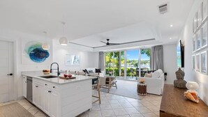 Een moderne keuken met een centraal eiland, een zithoek met een bank en stoelen, en een grote schuifdeur naar een balkon.