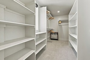 A walk-in closet with white shelving units and a hanging rod.