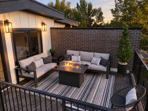 An outdoor patio with a fire pit, seating area, and a brick wall. - LoHi 5BR | Rooftop Fire Pit | Theater | Gym (Denver)