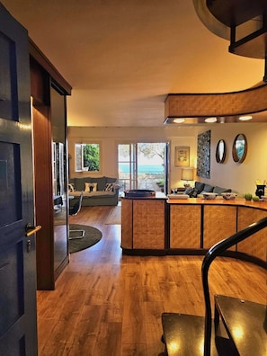 Uma sala de estar moderna com um banco de madeira curvo, um sofá e vista para o mar através de grandes janelas.