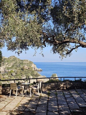 Una terrazza con pavimento in pietra, arredi da esterno e vista sul mare.