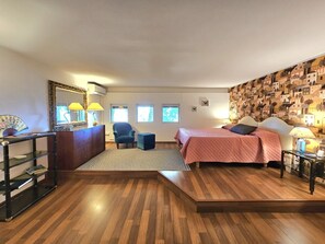 Una camera da letto con un letto, una sedia, una scrivania e uno specchio.