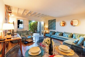 A modern living room with a sofa set, a coffee table, and a dining area with plates and glasses. - Villa Marina Taormina (Mazzaro')