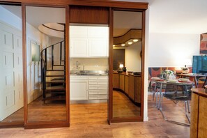 A modern kitchen with white cabinets, a stainless steel sink, and a dining area with a glass table and chairs. - Villa Marina Taormina (Mazzaro')