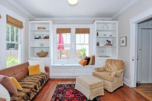 Ein gemütliches Wohnzimmer mit integriertem Sitzfenster, einer Couch, einem Sessel und einem Teppich.