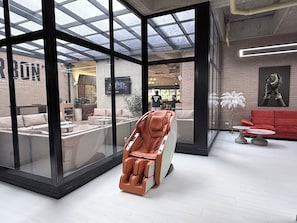 A modern interior with a massage chair, glass walls, a red sofa, and a brick wall. - Modern loft in Chicó, close to the 93 park (Bogotá)