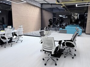 A modern conference room with a large table, white chairs, and a brick wall. - Modern loft in Chicó, close to the 93 park (Bogotá)