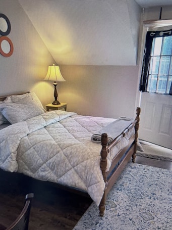 A room with a bed, a lamp, a chair, and a window.. Linden Leaf Gasthaus Inn Apartment Pet friendly Country walks, just off hwy 416