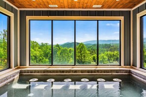 Wellnessbereich mit großem Fenster und Blick auf einen bewaldeten Gebirgszug.