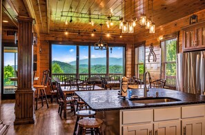Ein Holzinterieur mit einem großen Fenster, einer Kücheninsel und Blick auf die Berge.