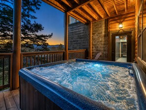 A hot tub on a wooden deck with a view of trees and mountains. - Luxury Smoky Mountain Cabin w/ Indoor Pool, Theater & Panoramic Views (Sevierville)