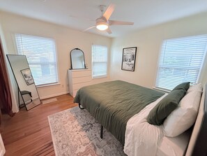 A bedroom with a bed, dresser, mirror, and ceiling fan. - Home near DFW Airport & Arlington World Cup. Perfect for groups and families. (Irving)