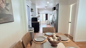 A dining area with a wooden table, chairs, and a central bowl. - Home near DFW Airport & Arlington World Cup. Perfect for groups and families. (Irving)