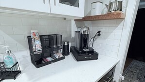 A kitchen with white cabinets, a coffee maker, a tea kettle, and a countertop with a soap dispenser. - Home near DFW Airport & Arlington World Cup. Perfect for groups and families. (Irving)