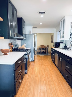 Una cocina moderna con armarios negros, un refrigerador de acero inoxidable y piso de madera.