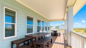 A covered outdoor deck with wooden benches and a table, overlooking a beach. - MR288 Shared Pools, Golf Cart Included, Pet Friendly (Port Aransas)