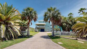 A pathway leading to a two-story building with a white facade and a blue garage door. - MR288 Shared Pools, Golf Cart Included, Pet Friendly (Port Aransas)