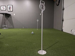 Una habitación con suelo de césped artificial, un poste señalizado y cuadros en la pared.