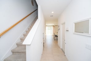 Eine Treppe führt zu einer Empore mit weißer Handlauf, einem Essbereich mit Stühlen und Tisch sowie einem Fenster mit Aussicht.