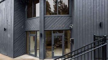 A modern building with a two-story entrance, large glass doors, and a metal staircase.
