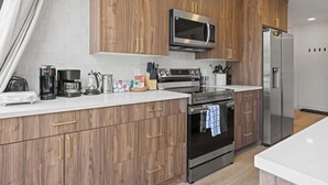 Una cucina moderna con mobili in legno, elettrodomestici in acciaio inossidabile e un piano di lavoro bianco.