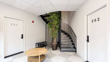 A hallway with a staircase, a potted plant, and a round table.