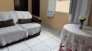 Een kamer met een bank, een tafel met een vaas en een raam met gordijnen.