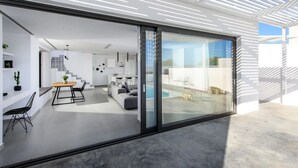 A modern interior with a dining area, sofa, and a view of the outside. - Luxury 2BR Cretan Villa Near Hersonissos Beaches (Hersonissos)