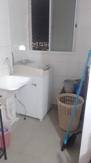 A small, clean bathroom with a sink, a window, and a laundry basket. - Vrbo Property (Uberaba)