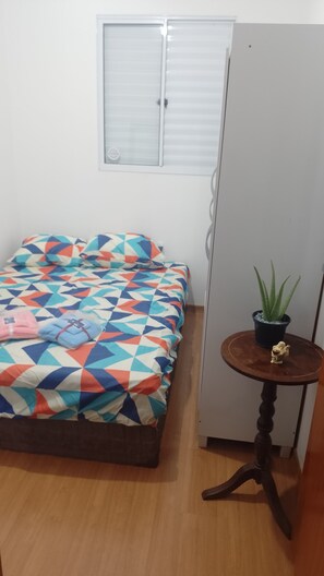 A bedroom with a bed, a small table with a plant, and a wardrobe. - Vrbo Property (Uberaba)