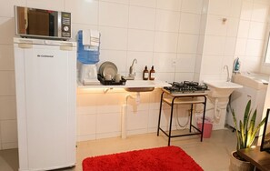 A compact kitchen with a microwave, sink, gas stove, and a water dispenser. - Apartment 10 minutes from downtown Uberaba! (Uberaba)