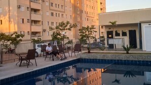 A high-rise building with a swimming pool, outdoor seating, and a clear sky.