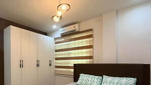 Quarto com cama, guarda-roupa e janela com persianas.