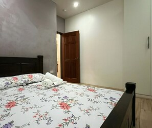 Un dormitorio con cama, una puerta de madera y un interruptor de luz en la pared.