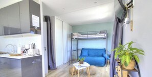 A compact room with a bunk bed, kitchenette, and a small table with a plant. - L'Atelier - SAINT VERAND (SAINT VERAND)